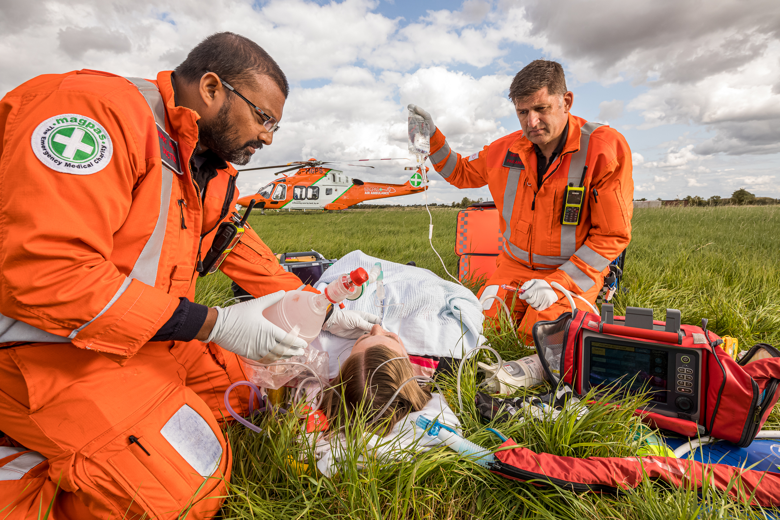 Two paramedics tend to patient on grass.